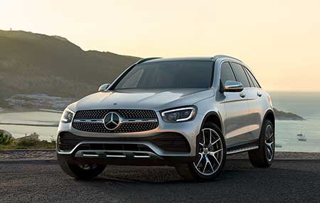 A silver Mercedes-Benz GLC parked by the lake during a sunset