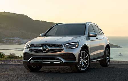 A silver Mercedes-Benz GLC parked by the lake during a sunset