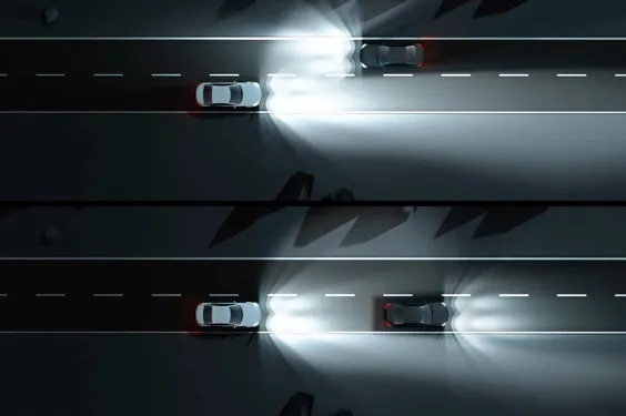 Un véhicule circulant sur une route sombre, faisant face au trafic venant en sens inverse avec ses phares allumés.
